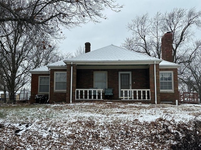 snow covered house featuring covered porch