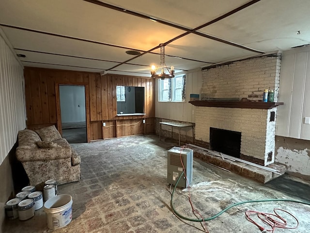 living room featuring a notable chandelier, a fireplace, and wooden walls