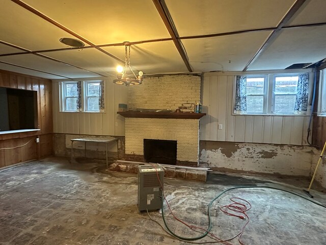 basement with plenty of natural light, a notable chandelier, and a brick fireplace