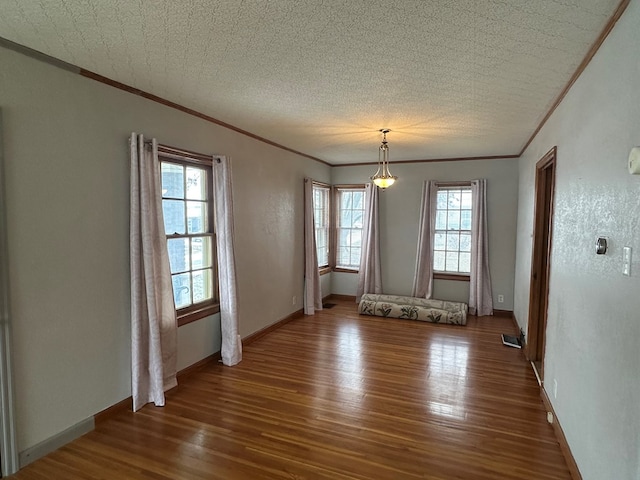 empty room with dark wood-type flooring, a textured ceiling, and ornamental molding