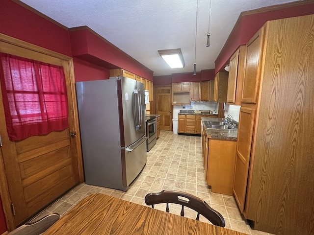 kitchen featuring appliances with stainless steel finishes, a textured ceiling, hanging light fixtures, and sink