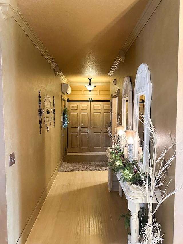 corridor featuring baseboards, a wall unit AC, wood finished floors, and crown molding