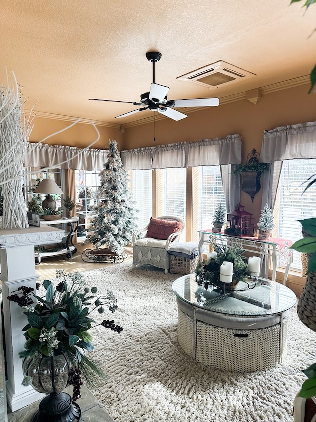 living room with ceiling fan, a textured ceiling, visible vents, and crown molding