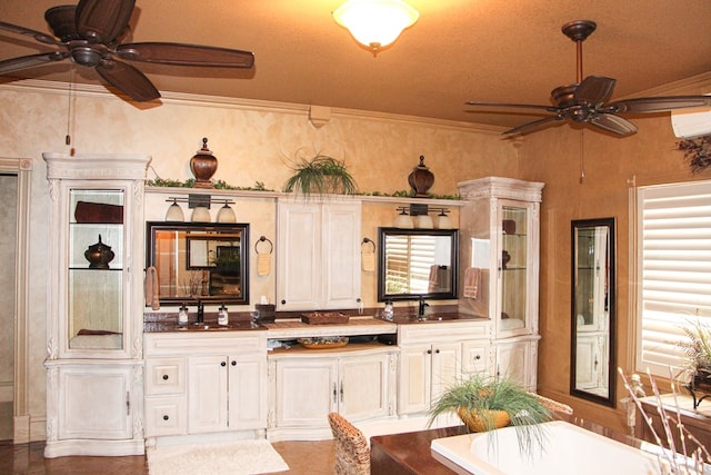 interior space with a sink, a ceiling fan, an AC wall unit, dark countertops, and crown molding