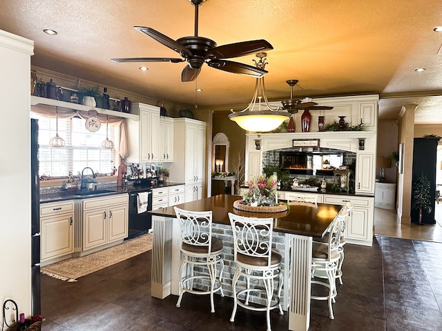 kitchen featuring a ceiling fan, dark countertops, dishwasher, a textured ceiling, and a center island
