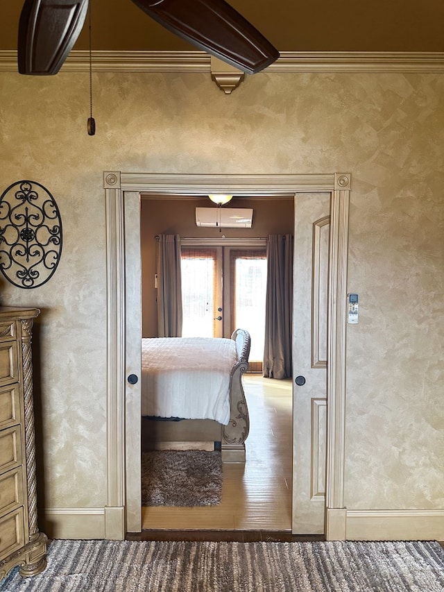 bedroom with french doors, a textured wall, baseboards, and wood finished floors