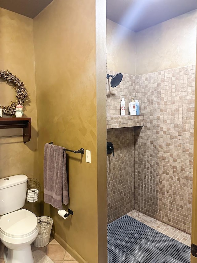 full bath with toilet, baseboards, tiled shower, and tile patterned floors