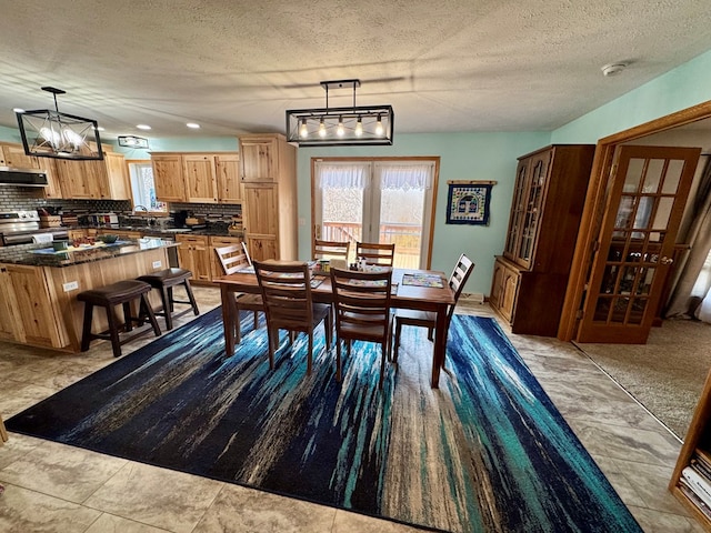 dining room with a notable chandelier, plenty of natural light, and a textured ceiling