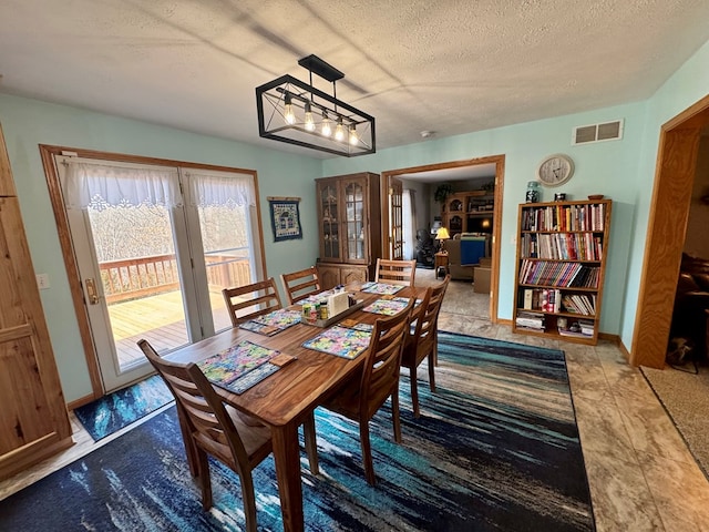 dining area featuring baseboards, visible vents, and a textured ceiling