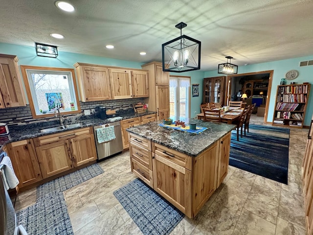 kitchen featuring a sink, decorative backsplash, stainless steel dishwasher, and a center island