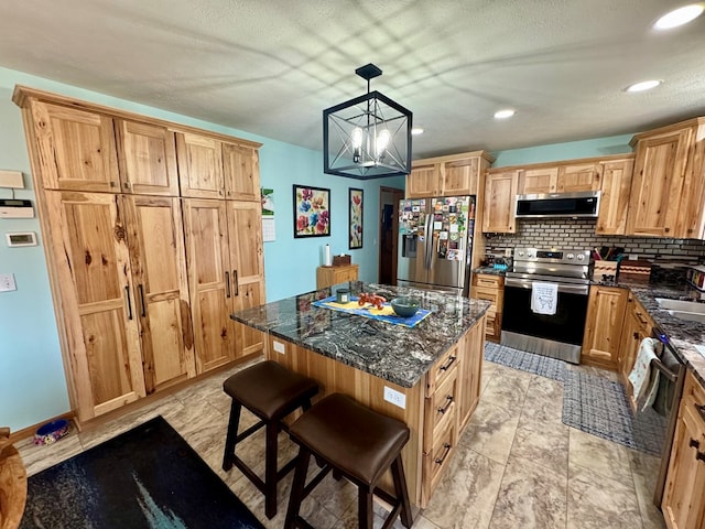 kitchen featuring dark stone countertops, a kitchen island, decorative backsplash, appliances with stainless steel finishes, and a kitchen breakfast bar