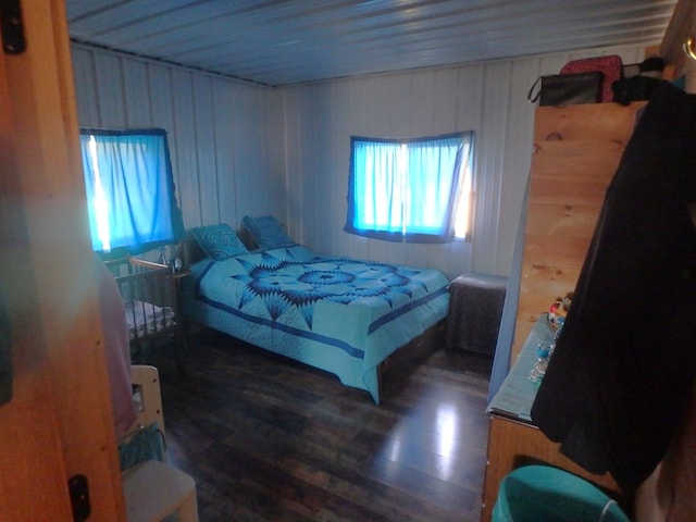 bedroom with wood walls and dark hardwood / wood-style flooring