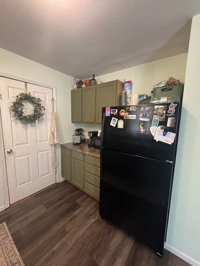 313 E 6th St, Milan, MO 63556 - kitchen with baseboards, freestanding refrigerator, dark countertops, a textured ceiling, and dark wood-type flooring