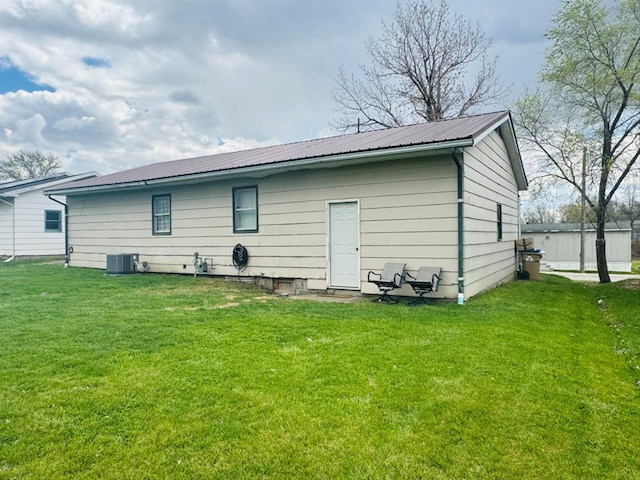 rear view of property featuring a yard, cooling unit, and metal roof