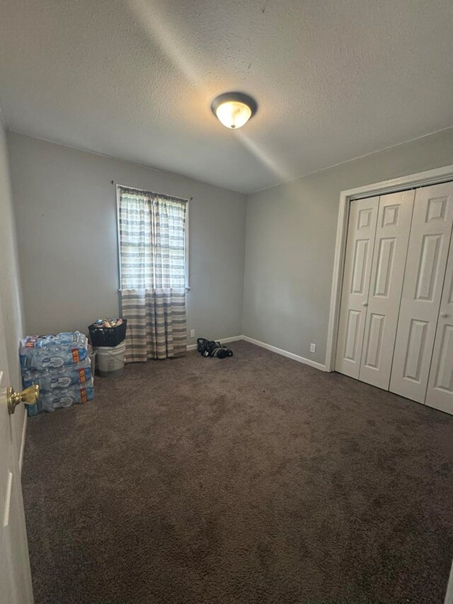 313 E 6th St, Milan, MO 63556 - unfurnished bedroom featuring carpet floors, baseboards, a closet, and a textured ceiling