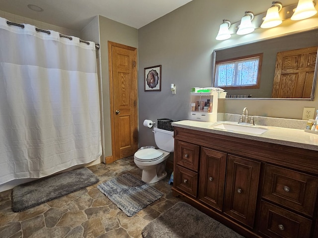 full bath featuring a shower with shower curtain, stone finish flooring, toilet, and vanity