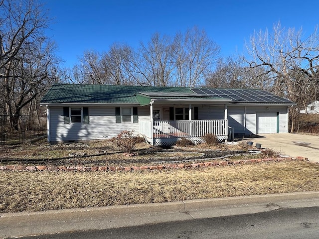 113 N Cottage Grove Ave, Kirksville, MO 63501 - ranch-style house with solar panels, covered porch, concrete driveway, a garage, and metal roof