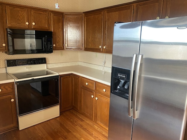 911 Cherry St, Chillicothe, MO 64601 - kitchen featuring light countertops, dark wood-type flooring, electric stove, black microwave, and stainless steel refrigerator with ice dispenser