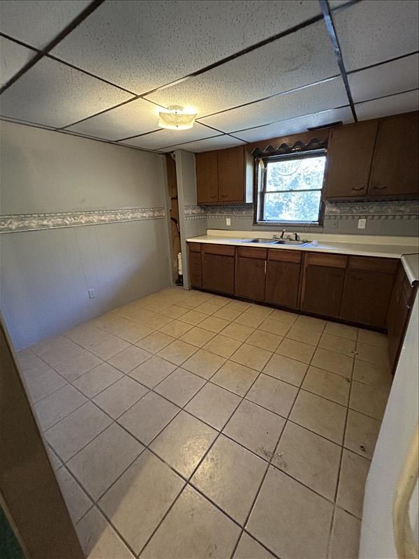 803 Coates St, Macon, MO 63552 - kitchen with backsplash, light countertops, light tile patterned floors, and a paneled ceiling