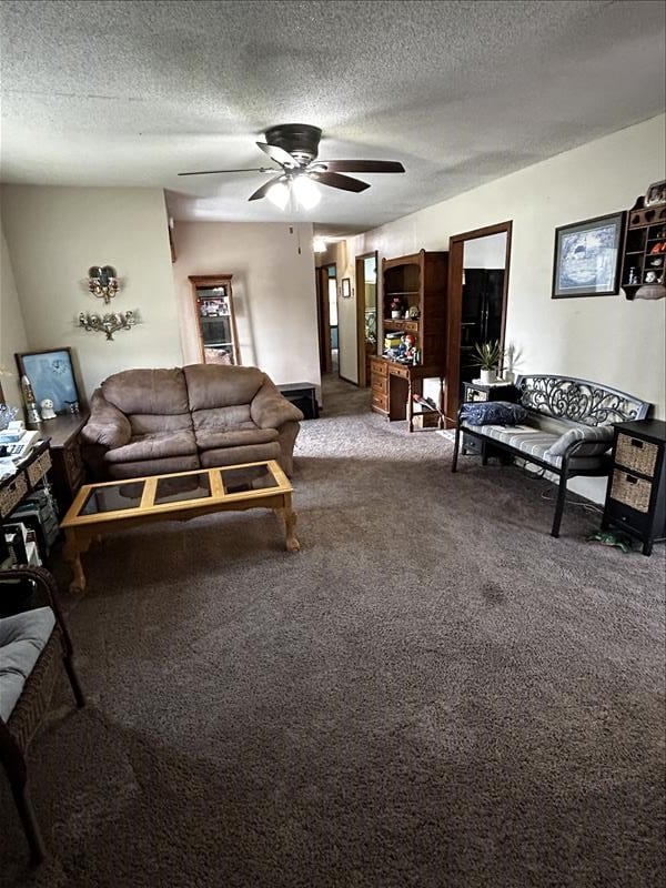 carpeted living room featuring ceiling fan and a textured ceiling