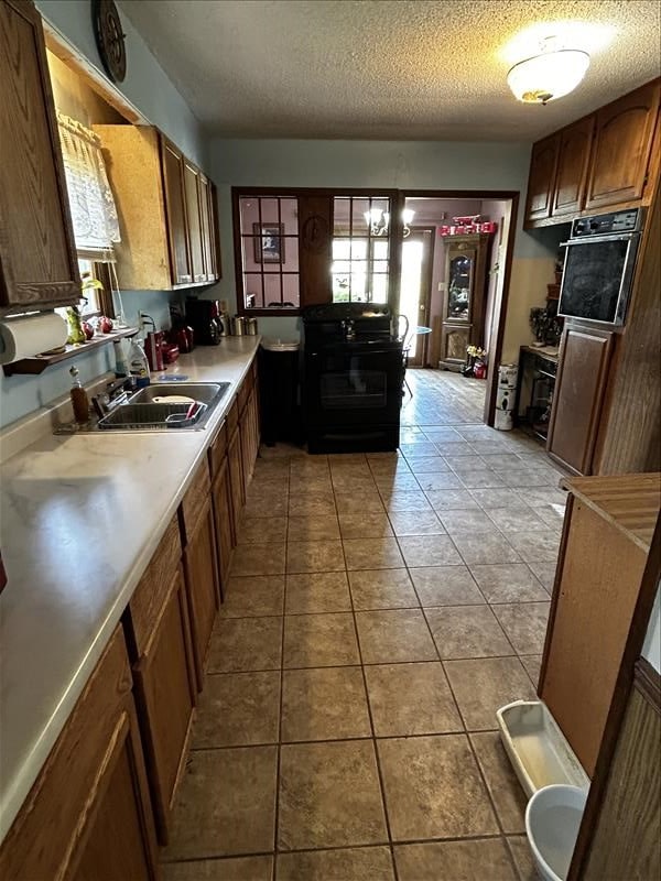 803 Coates St, Macon, MO 63552 - kitchen with a textured ceiling, light countertops, a sink, and light tile patterned floors