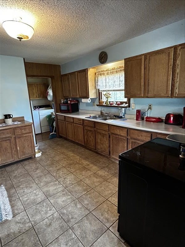 803 Coates St, Macon, MO 63552 - kitchen featuring a sink, separate washer and dryer, a textured ceiling, brown cabinetry, and black appliances