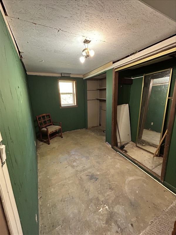 803 Coates St, Macon, MO 63552 - unfurnished bedroom with unfinished concrete flooring, multiple closets, and a textured ceiling