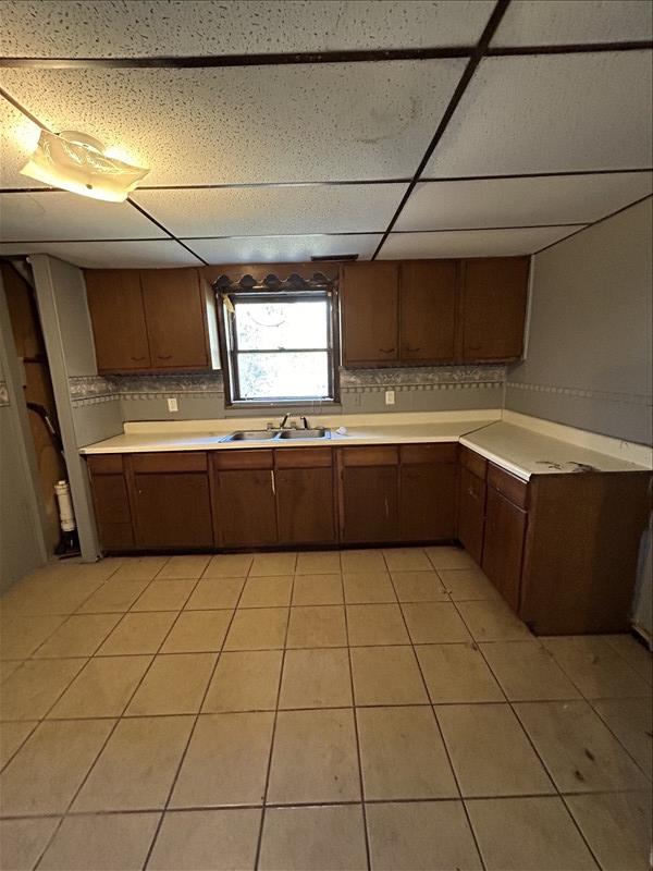 803 Coates St, Macon, MO 63552 - kitchen featuring light tile patterned flooring, light countertops, a sink, and a drop ceiling