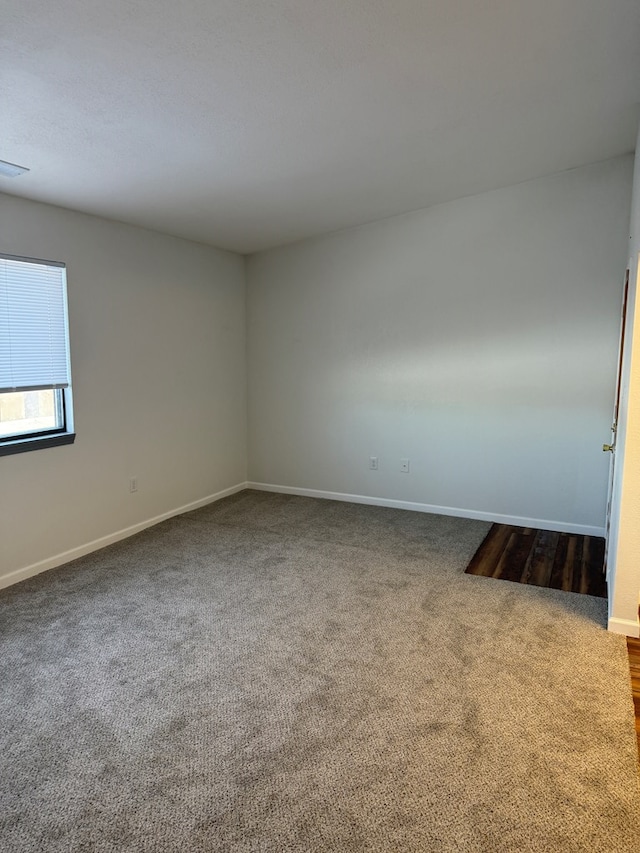 spare room featuring carpet flooring and baseboards