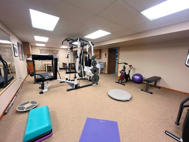 workout area with a sink, carpet, baseboards, and a drop ceiling