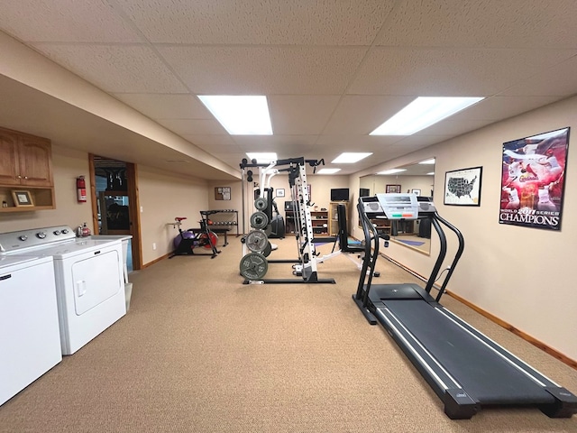 exercise room with a paneled ceiling, carpet flooring, independent washer and dryer, and baseboards