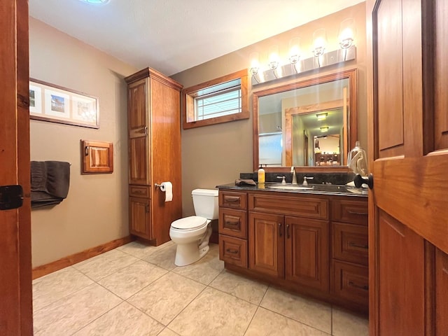 bathroom with tile patterned flooring, baseboards, vanity, and toilet