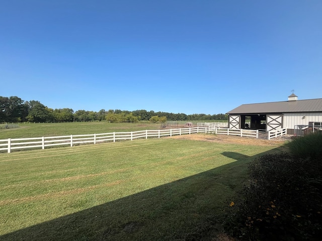 view of yard featuring an outdoor structure, an exterior structure, and a rural view