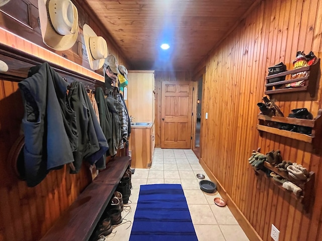 mudroom featuring wooden ceiling, wooden walls, and light tile patterned floors