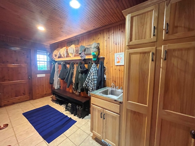 mudroom featuring light tile patterned floors, wood walls, a sink, and wood ceiling