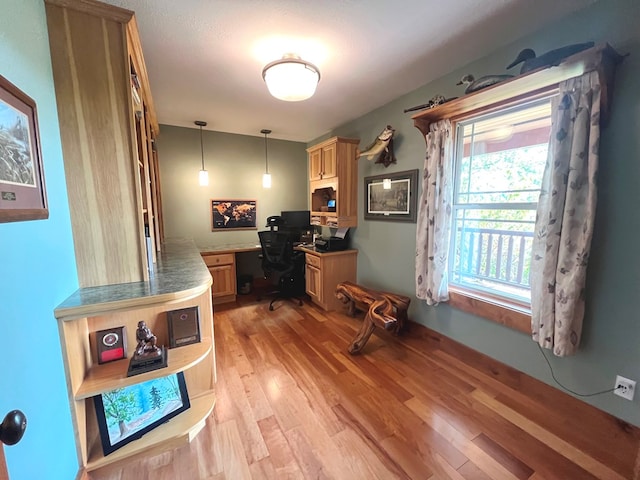 office with built in desk and light wood-style flooring