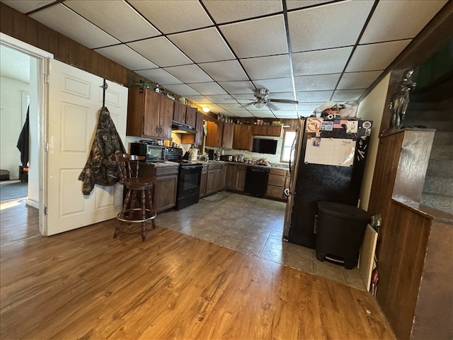 kitchen featuring a paneled ceiling, black appliances, sink, ceiling fan, and wood-type flooring