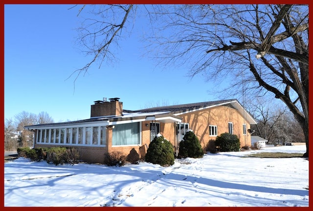 view of front facade with brick siding and a chimney