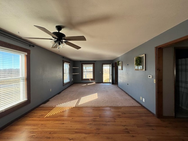 interior space featuring vaulted ceiling, ceiling fan, a textured ceiling, and wood finished floors