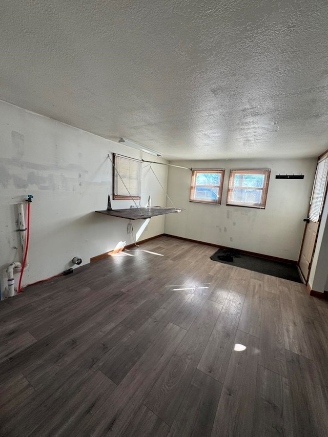 unfurnished room featuring a textured ceiling, baseboards, and wood finished floors