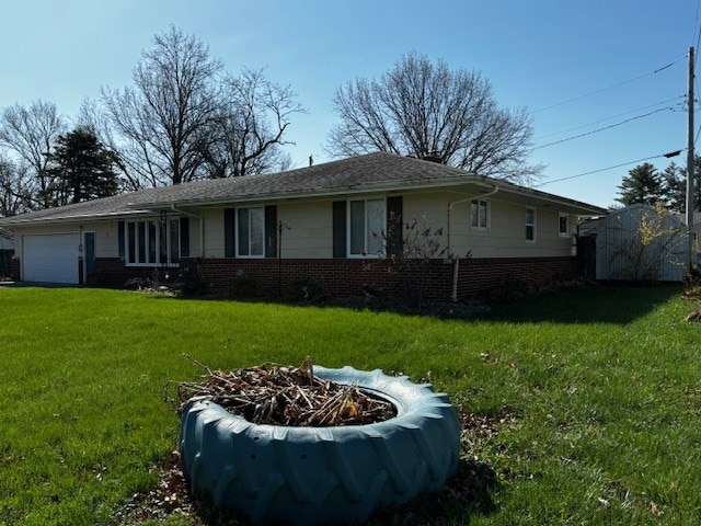 2 Center Dr, Kirksville, MO 63501 - view of front of house featuring an attached garage, an outdoor fire pit, a front lawn, and brick siding