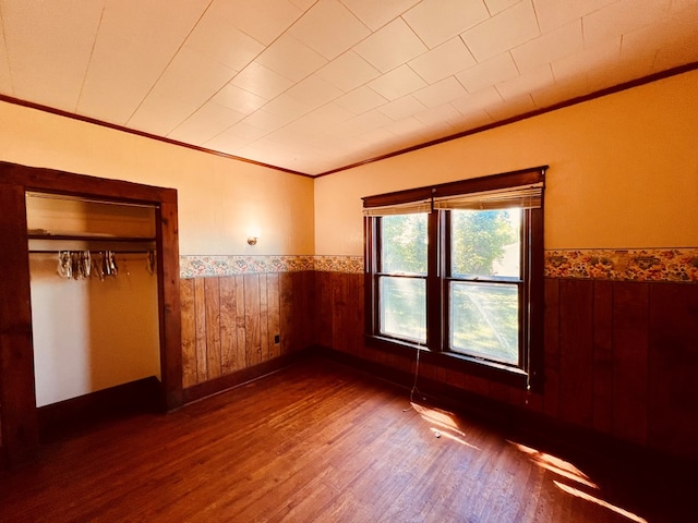 unfurnished bedroom featuring dark hardwood / wood-style floors, ornamental molding, and a closet