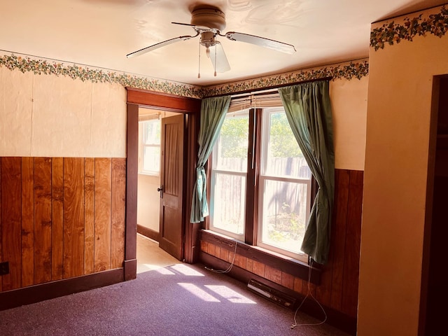 spare room with light colored carpet, ceiling fan, and wood walls