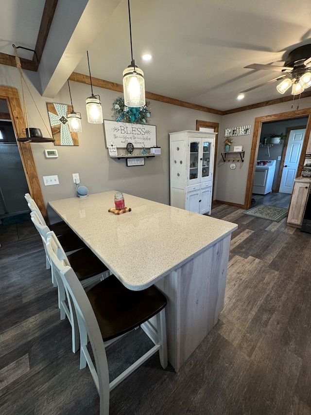 kitchen featuring decorative light fixtures, light countertops, washer / dryer, a peninsula, and a kitchen bar