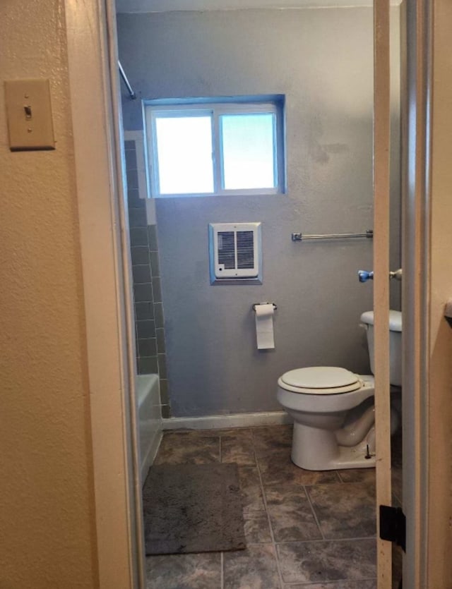 bathroom with toilet, tiled shower / bath, and heating unit