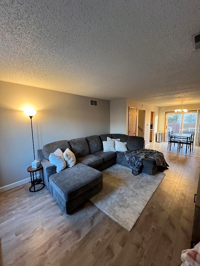 living room featuring hardwood / wood-style floors, a textured ceiling, and a notable chandelier