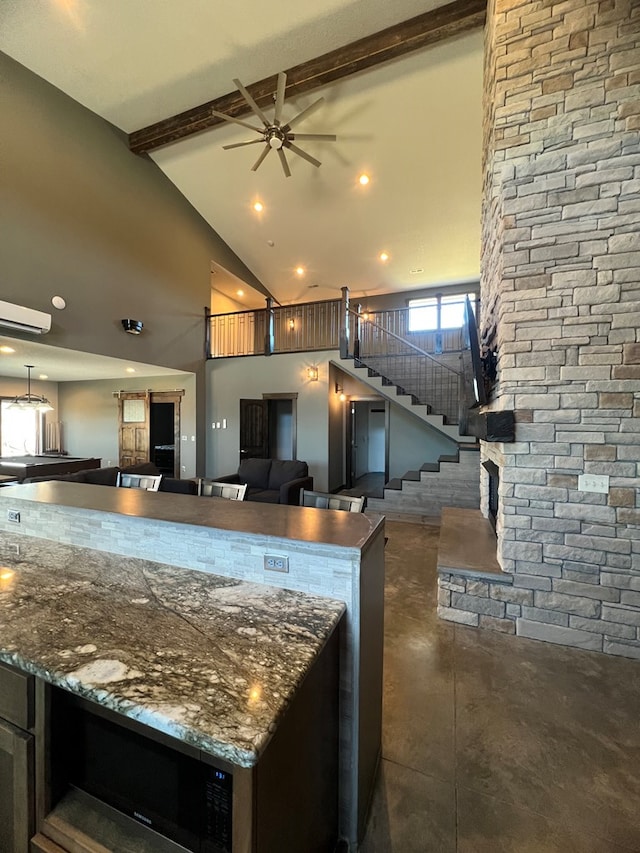 kitchen with beam ceiling, open floor plan, ceiling fan, dark stone countertops, and high vaulted ceiling