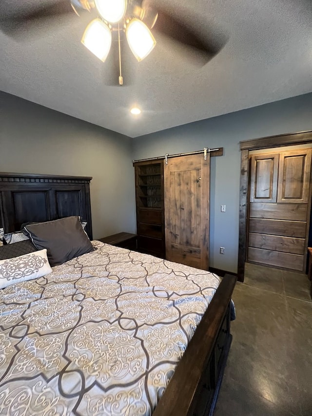 bedroom with dark carpet, a barn door, ceiling fan, vaulted ceiling, and a textured ceiling