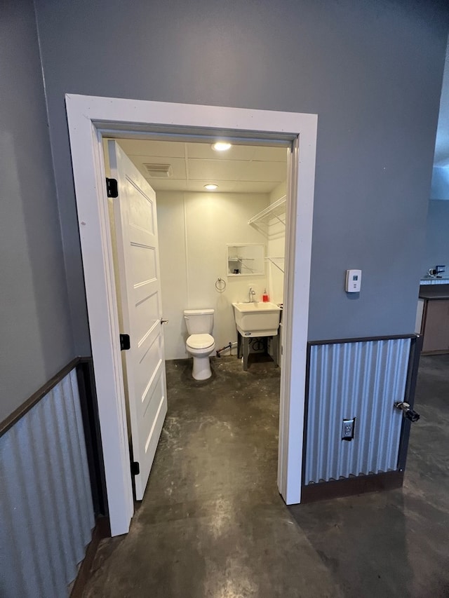 bathroom featuring toilet, unfinished concrete floors, visible vents, and a sink