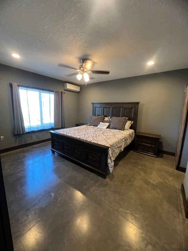 bedroom with a textured ceiling, concrete floors, a wall mounted AC, and baseboards